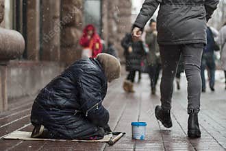 Hungry homeless beggar woman beg for money on the urban street in the city from people walking by, social documentary concept