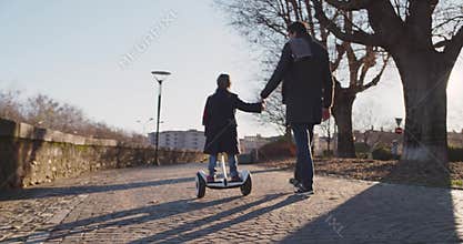 Daughter child girl learning segway riding with dad teaching in city.Modern future transport technology.Active safety