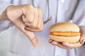 Doctor hand holding unhealthy fast food burger