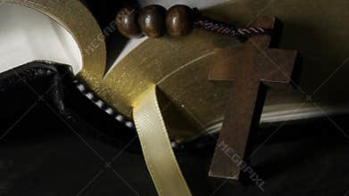 Light rising over rosary in front of holy bible