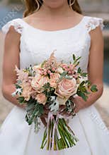 The bride holds a pink-peach wedding bouquet
