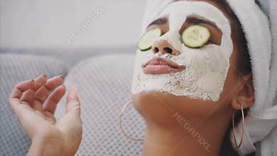 A beautiful young woman gets a face mask in the spa center, lying with cucumbers in her eyes. Happy and gets a lot of