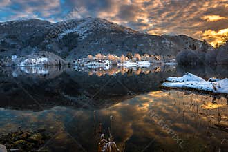 Winter Landscape with Snowy Mountains, Colorful Clouds and Lake Reflection at Sunset