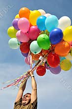 Unidentified man holding bunch of multicolored balloons