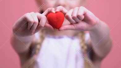 Little girl showing toy heart at camera closeup, charity and kindness concept