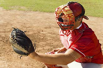 Baseball catcher crouching on field