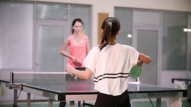 Ping pong playing. Young woman playing table tennis with her friend. Back view