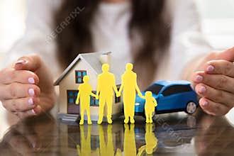 Businesswoman Protecting House, Car And Family Figures