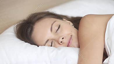 Calm woman sleeping well in comfortable bed on soft pillow
