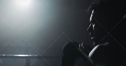 Male boxer training in the dark ring. Slow motion. Silhouette. Boxing concept.