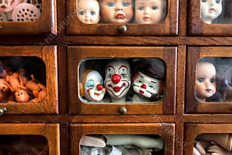 Body parts and faces of crying kids and smiley actors. Dolls inside wooden house for play. Broken toys for game