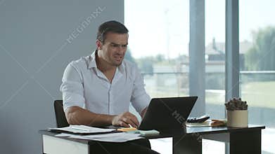Business man receiving bad letter by email. Serious freelance working on laptop.