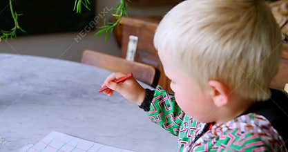 Boy drawing with coloured crayon on paper at home 4k