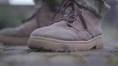 Soldier`s laced up boots close up. Shoelaces fluttering in the wind. Military boots on the man`s feet. Military and