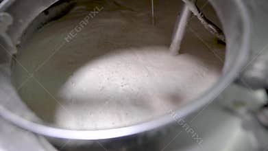 Stirring wort in a large steel vessel on a brewery factory.