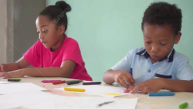 African American kids learning how to draw with crayon on table