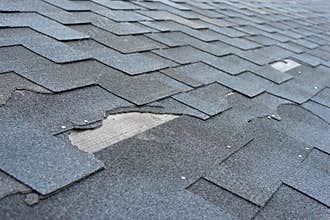 Ð¡lose up view of asphalt shingles roof damage that needs repair.