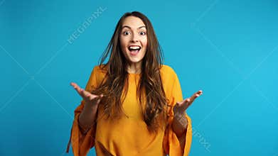 Happy amazed  woman saying yes and rejoices good news on blue background