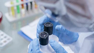 Male scientist working in the lab, looking into the microscope