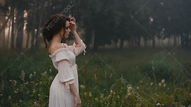 Beautiful girl in white dress posing on camera.