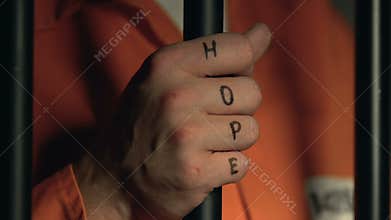Criminal with hope word on beaten fists holding cell bars, violence in jail
