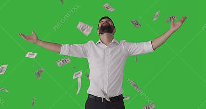 Man standing under raining banknotes over green screen