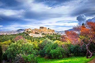 Acropolis with Parthenon. View through a frame with green plants, trees, ancient marbles and cityscape, Athens.