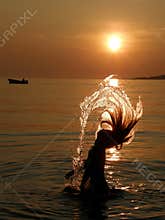 Girl have a fun in sea at sunset