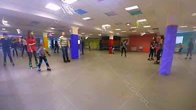 Many people of children and adults go roller-skating on the rollerdrom