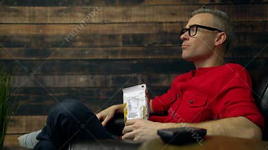 Upset man yells at TV while eating