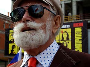 Man with a white beard wearing sunglasses and a hat. Street
