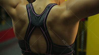 Close-up shot of muscular female athlete's back during active workout in the gym