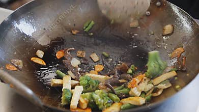 Professional cook frying vegetables with tofu at the street food festival. Process of cooking close up.