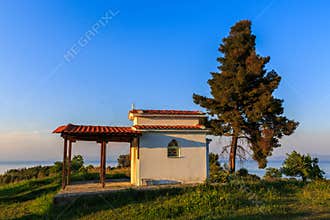 A lonely chapel under a tree on the hill of the sea coast in a c