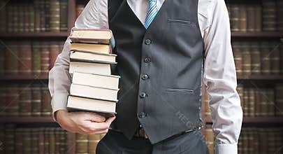 Student is holding many books in hands in library