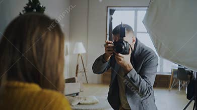 Professional photographer taking photos of model on digital camera working in photo studio