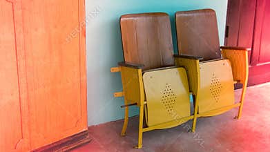 Close up of old wooden folding cinema chair or folding seat in front of Asian theater.