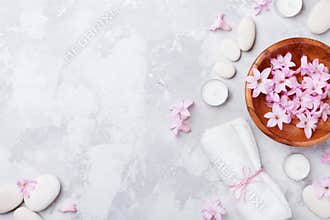 Aromatherapy, beauty, spa background with massage pebble, perfumed flowers water and candles on stone table top view. Flat lay.