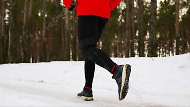 Close-up of foot running in winter on snow in sneakers through the forest. Slow motion. 120 frames per second