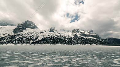 Mountain and frozen lake. Sun rays through clouds Timelapse 4K. Scenery landscape