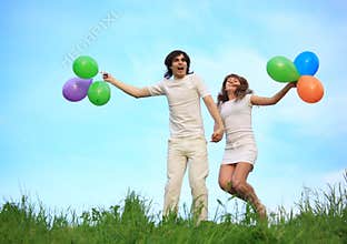 Couple stand in grass with balloons