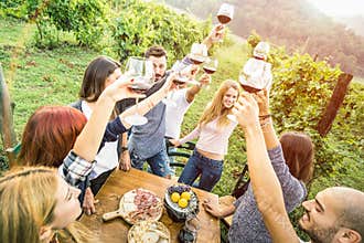 Young friends having fun outdoors drinking red wine at vineyard winery
