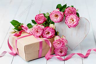 Rose flowers, wooden heart and gift box on blue rustic table. Beautiful greeting card for Birthday, Woman or Mothers Day.
