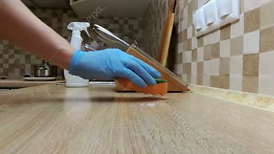 Cleaning the counter with spay and sponge in a kitchen.