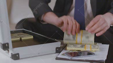 Businessman takes out dollar packs from briefcase, lots of money