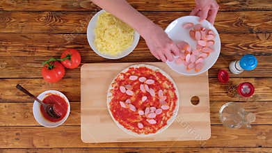 Woman making pizza and puts sausages on dough