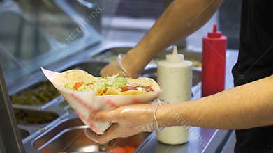 Chef adding vegetables to pita at kebab shop