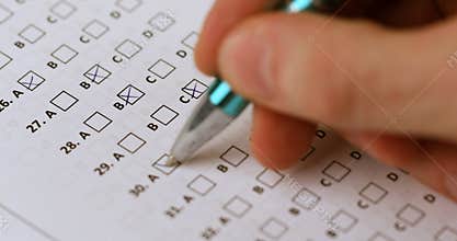 Student hand with pen fill in exam test answer sheet