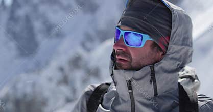 Climber mountaineer man portrait on snowy mount top in sunny day.Mountaineering ski activity. Skier people winter snow