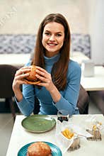 Woman Eating Burger In Fast Food Restaurant.